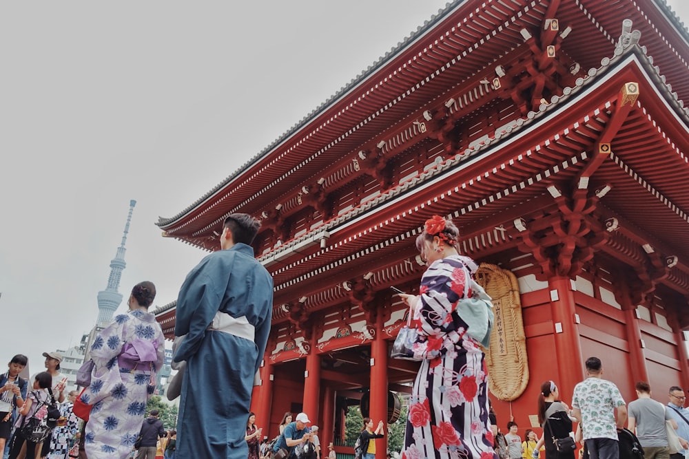 a group of people walking around a building with a red roof