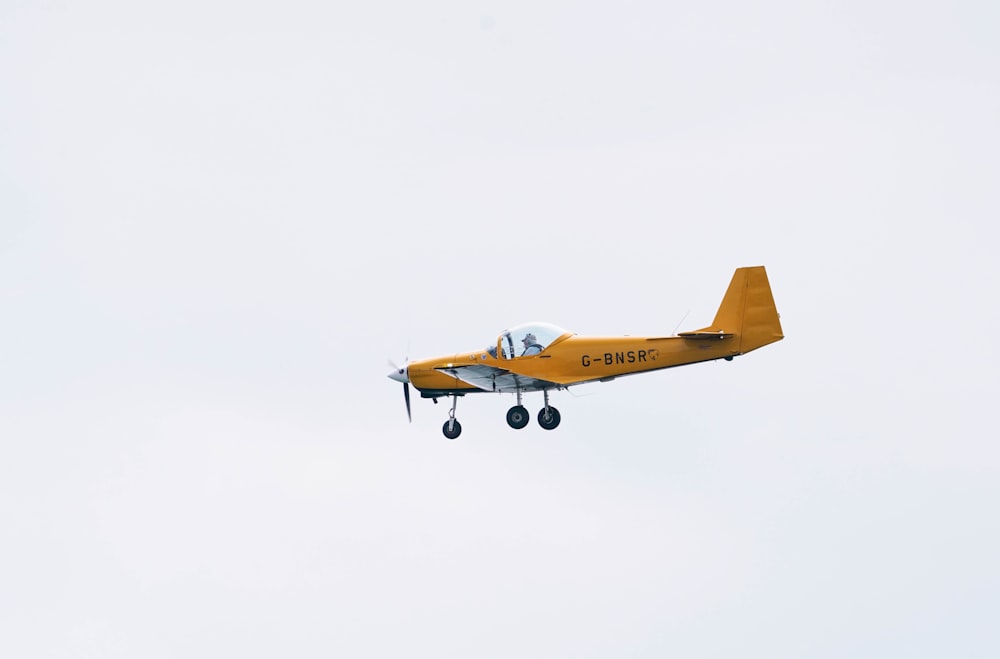 a yellow plane flying in the sky