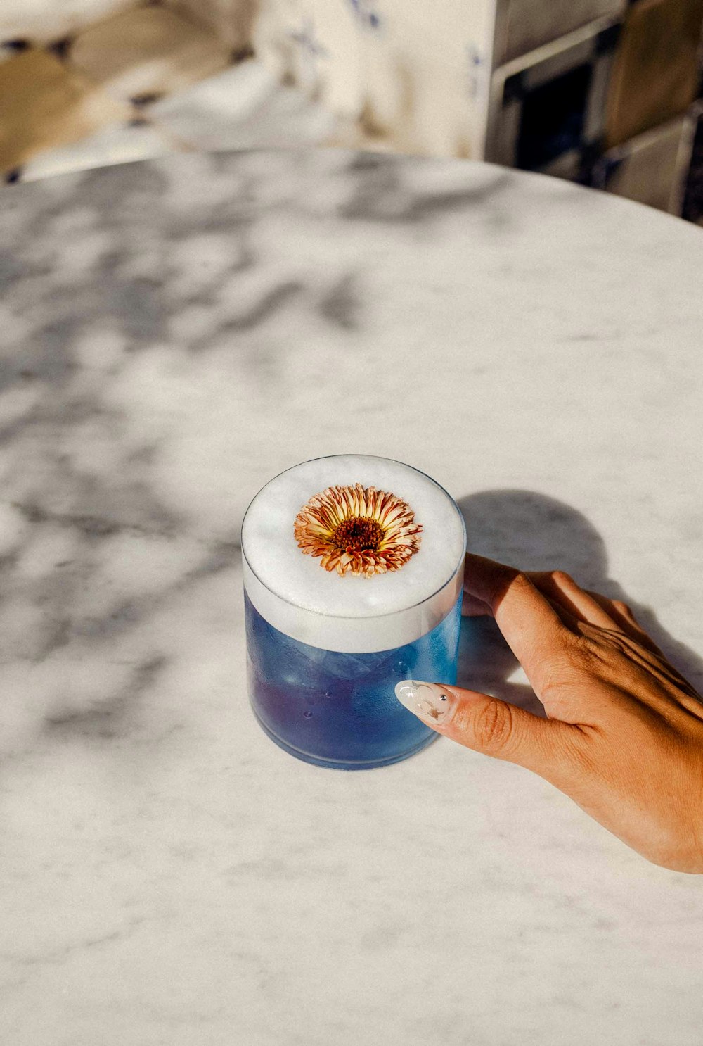 a hand holding a small cup of coffee