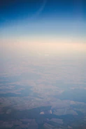 An overhead drone shot showing geometric farmland patterns under clear skies.
