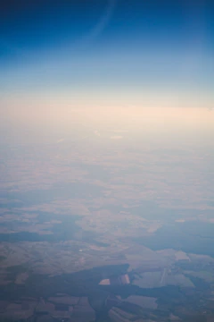 An overhead drone shot showing geometric farmland patterns under clear skies.