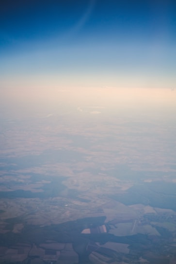 Aerial view of a vast agricultural landscape with fields and a clear blue sky.