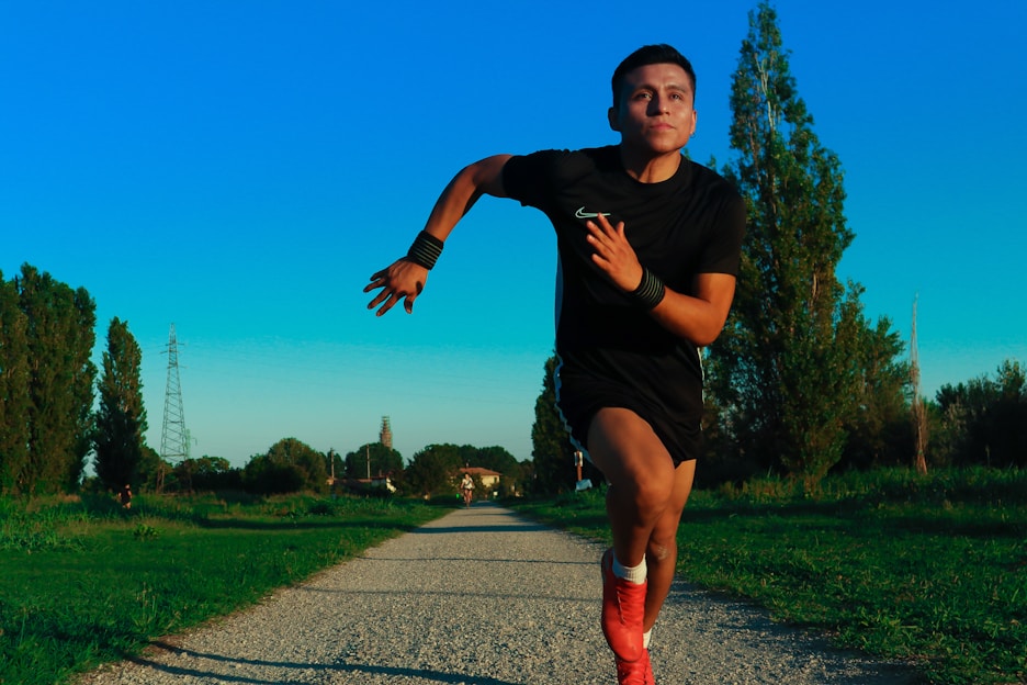 Athlete wearing a high-elasticity knee brace running on an outdoor trail with a focused expression.