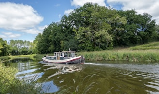 A small boat cruising along the clear waters of the German Channel with lush greenery in the background.
