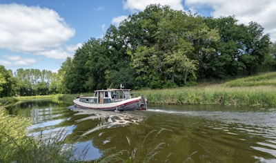 A small boat cruising along the clear waters of the German Channel with lush greenery in the background.