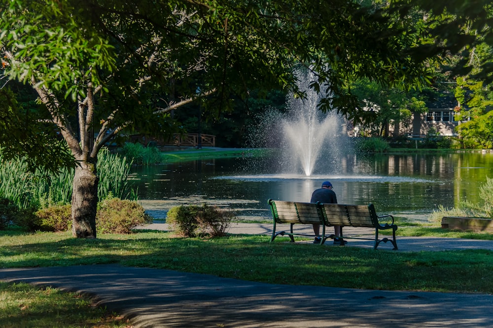 a person sitting on a bench in front of a fountain