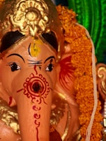 Close-up of an intricately carved statue of Maha Guru Shree Dattatreya surrounded by blooming marigolds.