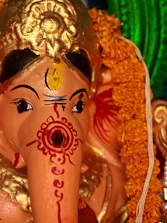Close-up of an intricately carved statue of Maha Guru Shree Dattatreya surrounded by blooming marigolds.