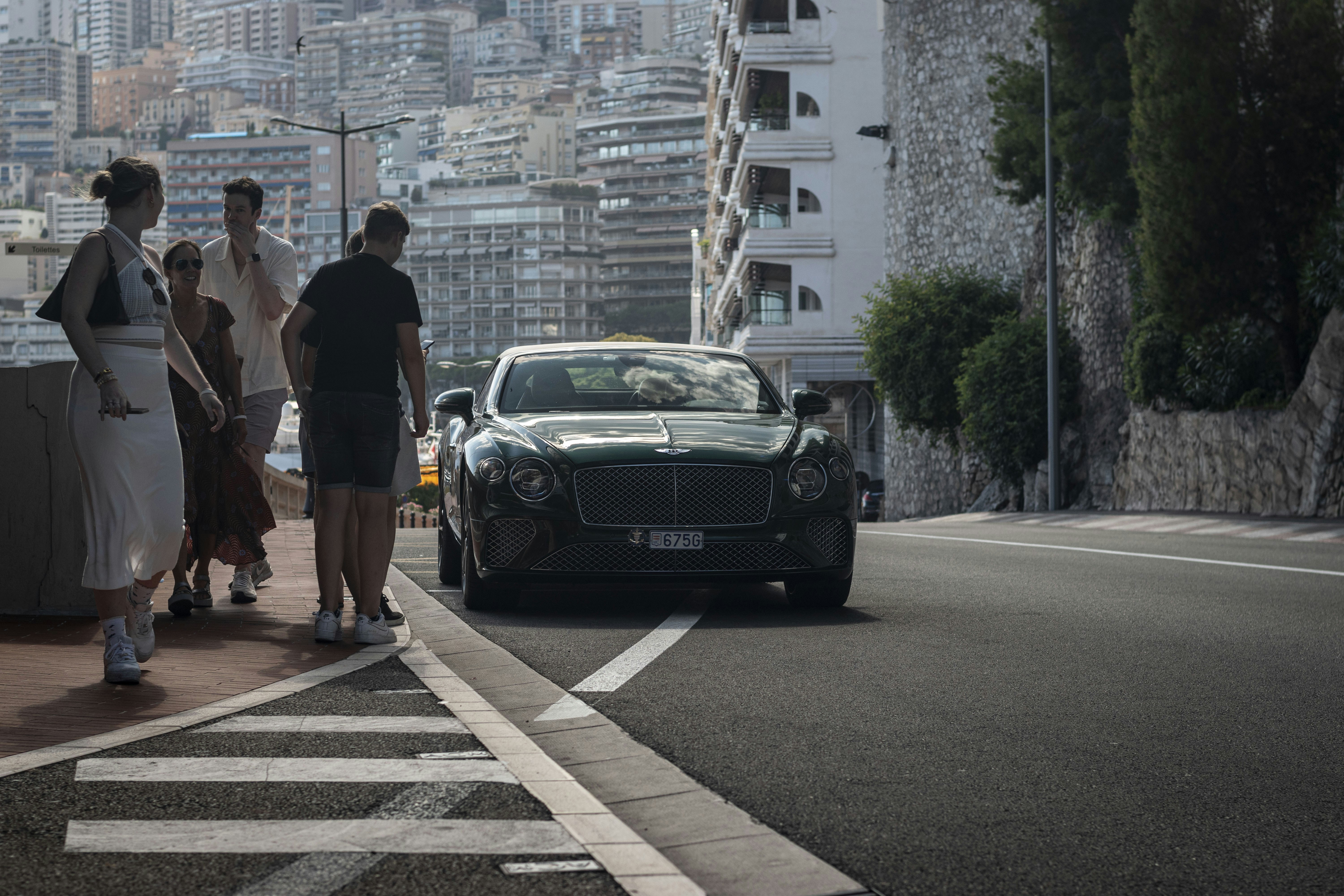 a group of people standing next to a car on a road