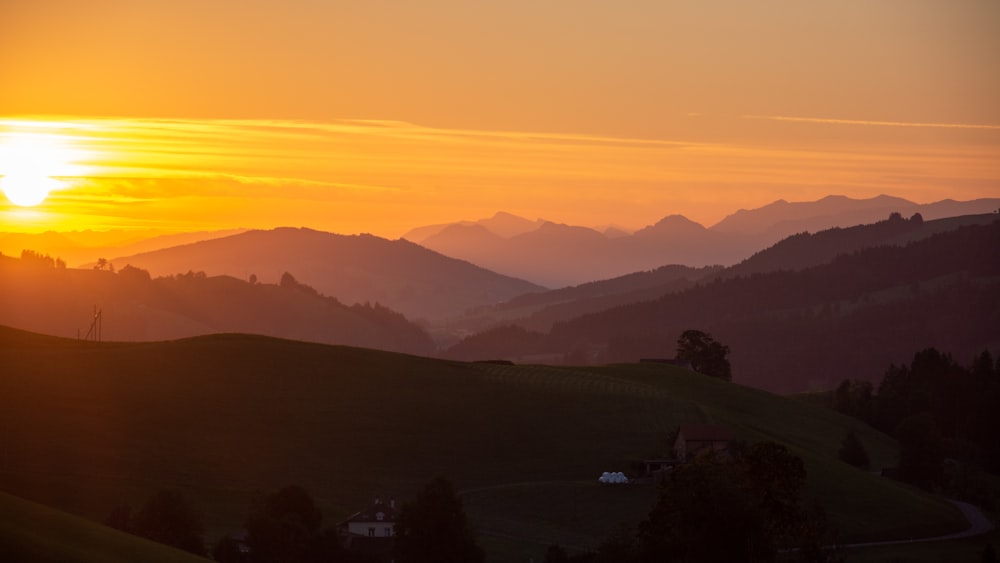 a landscape with hills and a sunset