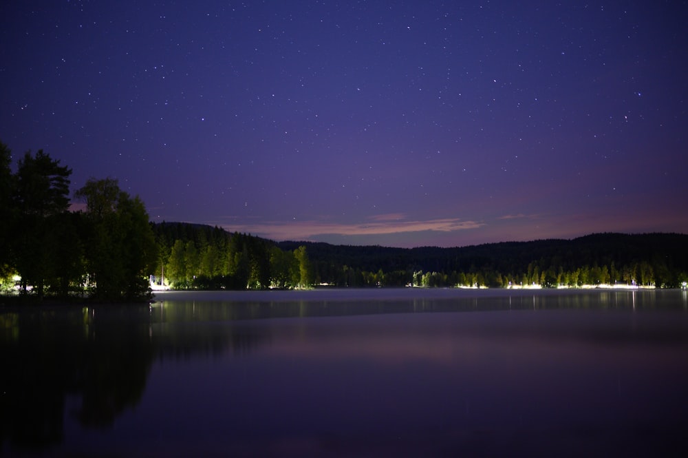 a lake with trees and a blue sky