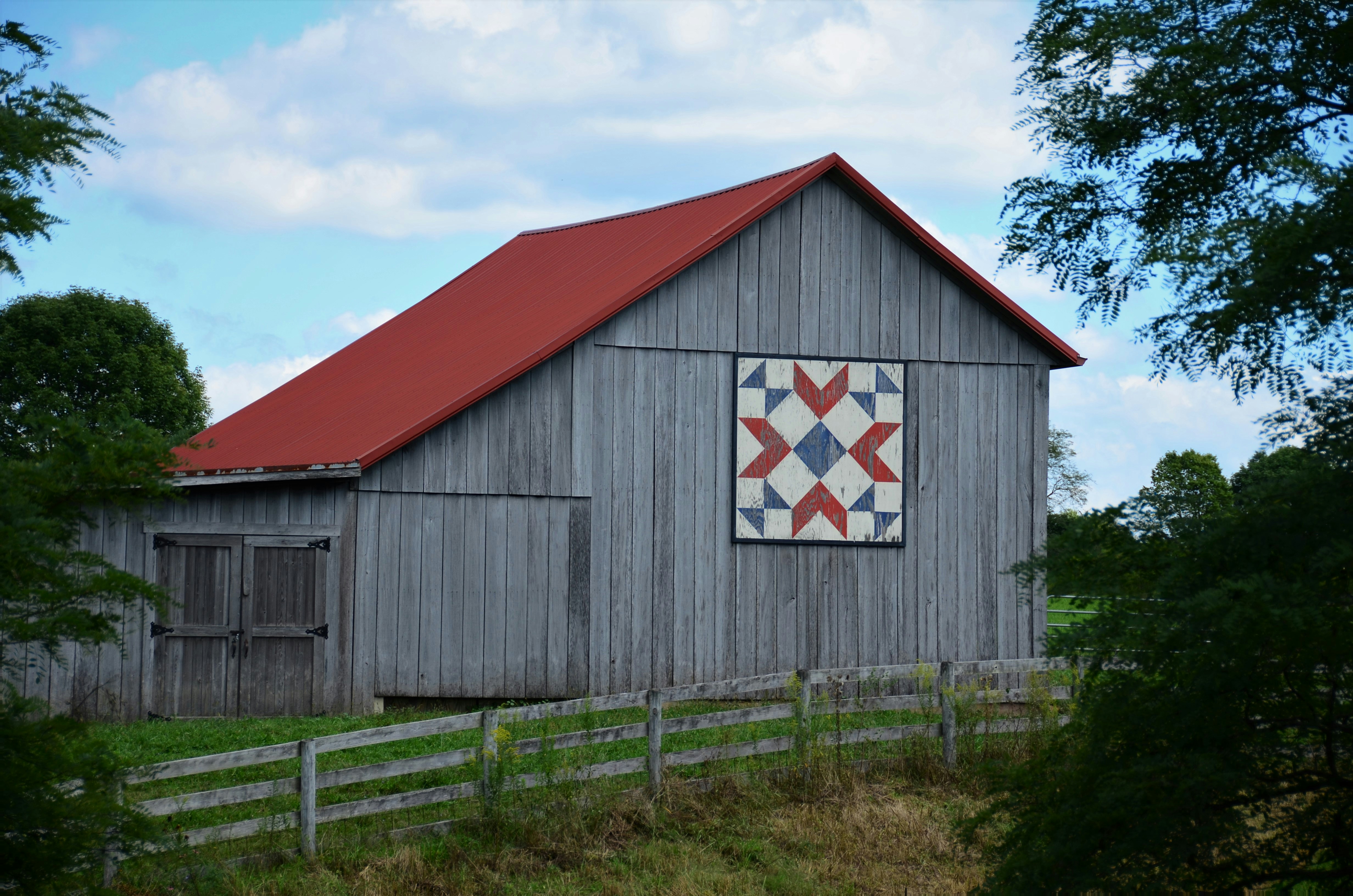 Gray barn with red roof and barn quilt