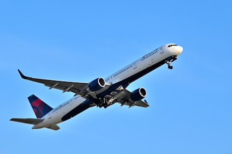 A sleek airplane taking off into a clear blue sky at sunrise.