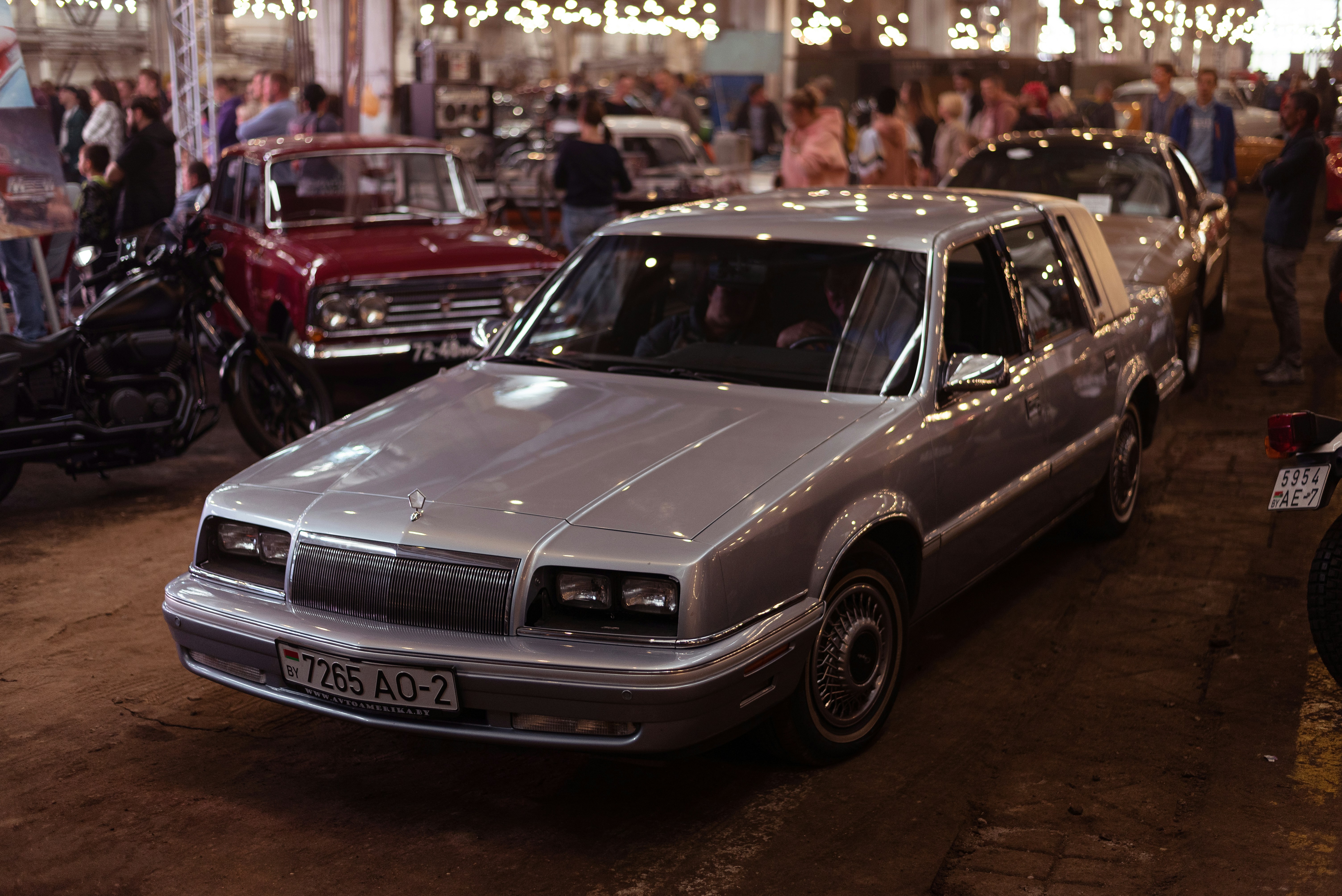 a silver car parked in a showroom with other cars
