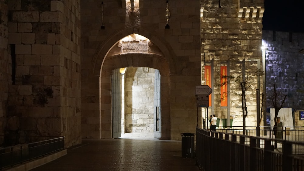 a stone walkway with a fence and a building with a sign on it