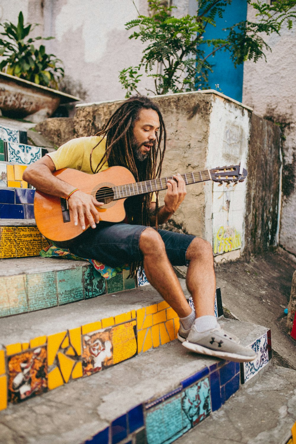 a man sitting on a ledge playing a guitar