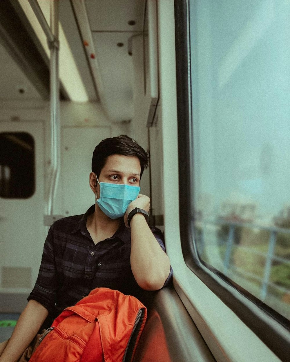 a man wearing a mask and sitting on a train