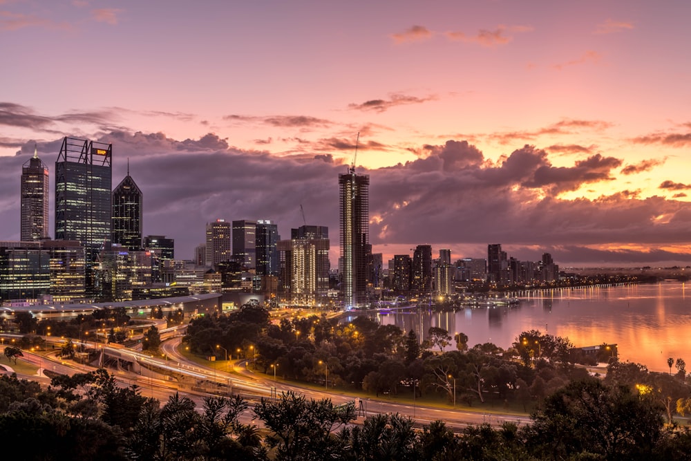 a city skyline with a river and a sunset