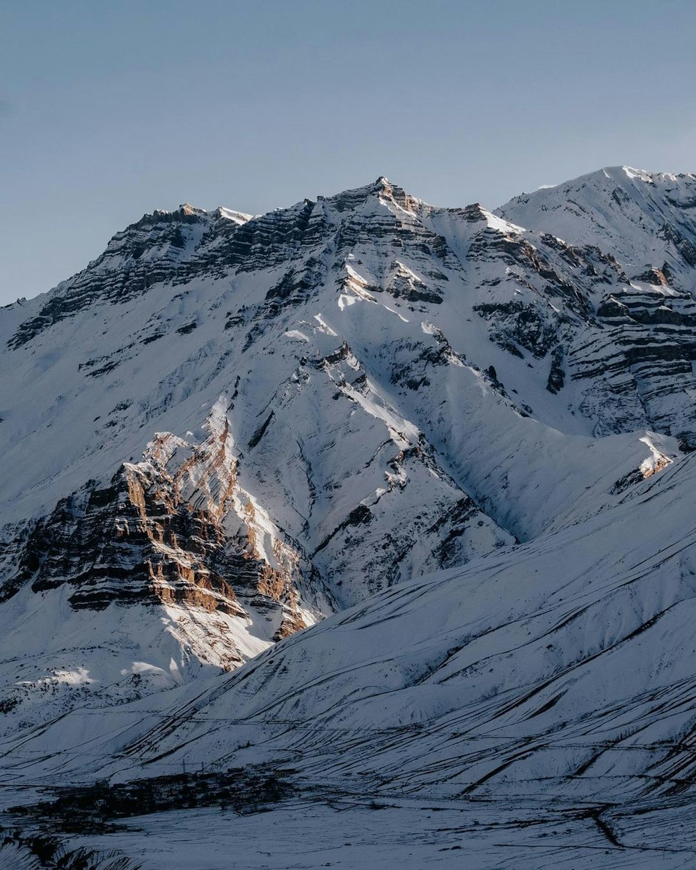 a snowy mountain with a lake below