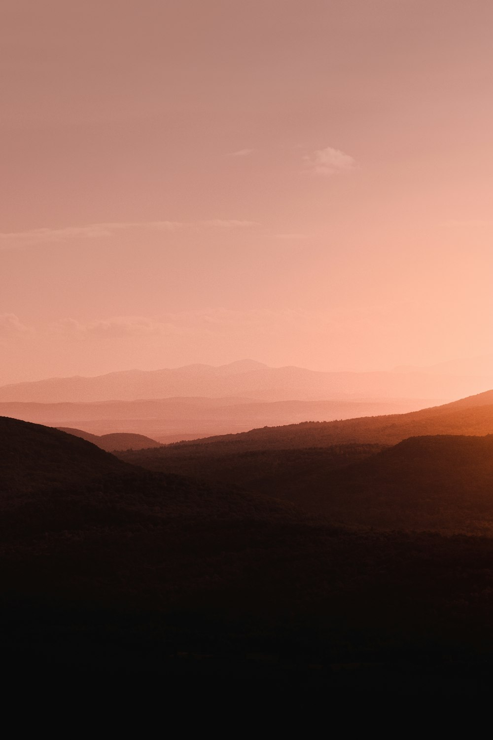 a landscape with hills and a pink sky