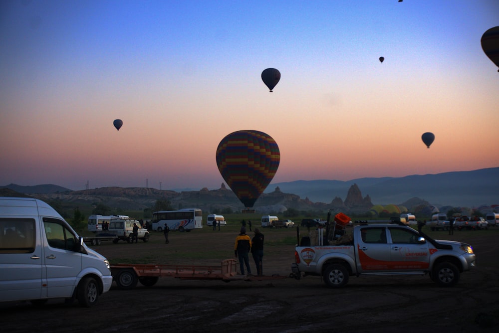 a group of people standing in front of a group of hot air balloons