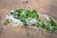 A clump of green seaweed mixed with white fibrous material lies on wet sand. The green seaweed has a vibrant color, while the white fibers add contrast. The surrounding sand has a smooth texture, with some small pebbles scattered around.