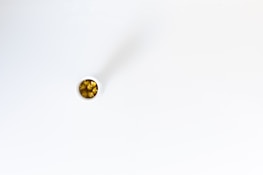 A small white container containing yellow capsules, possibly dietary supplements or medication, positioned on a smooth, white surface.