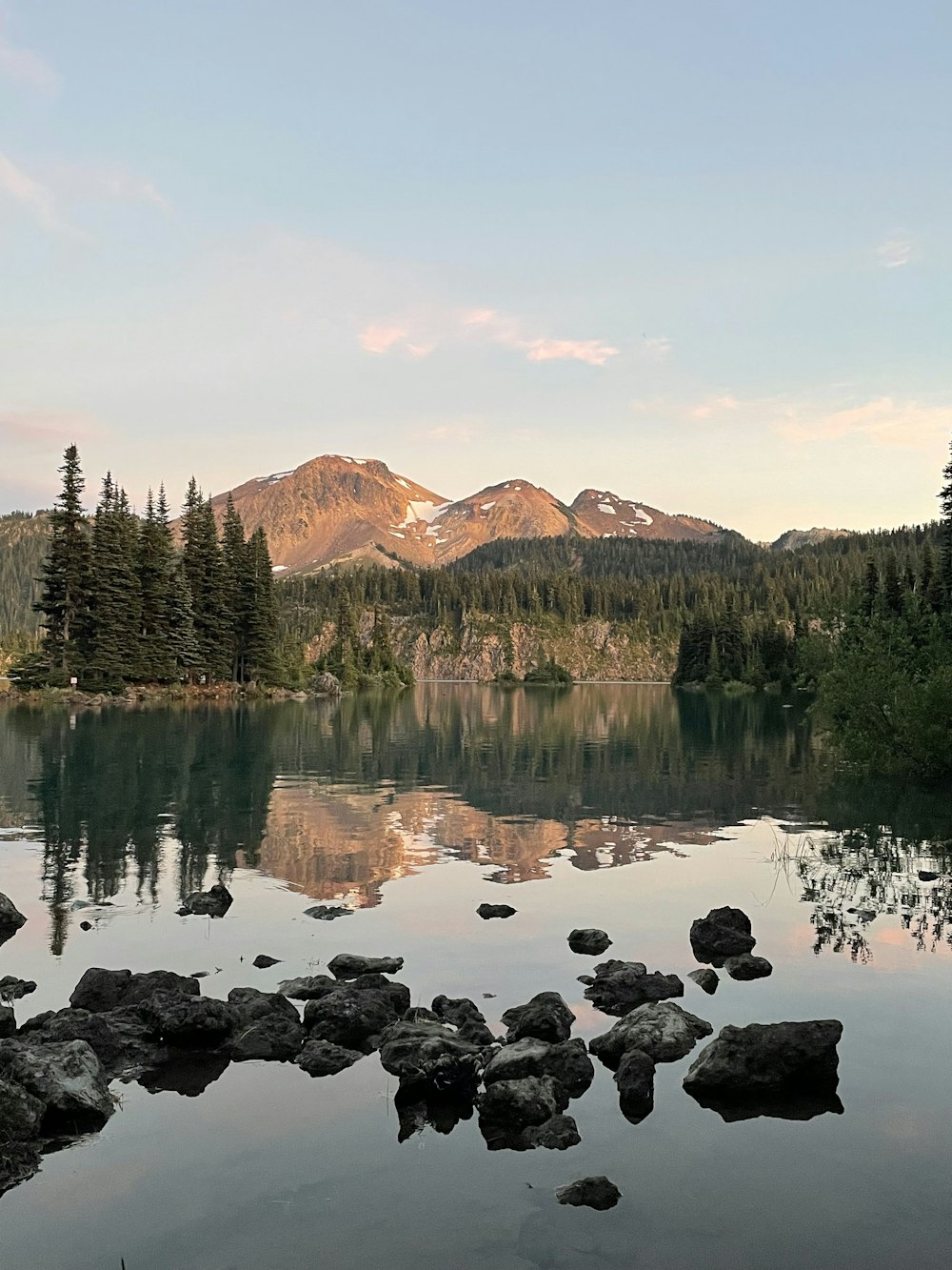 a lake with trees and mountains in the background