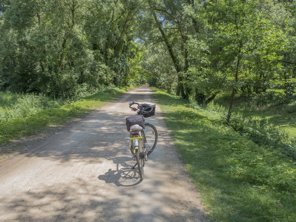 a person riding a bike on a dirt road surrounded by trees