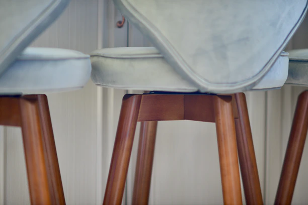 Close-up of a modern metal barstool with a cushioned seat and backrest.