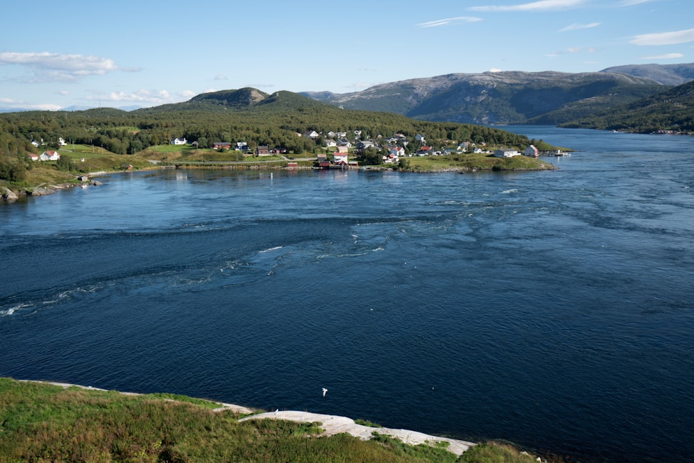 a body of water with houses and hills in the background