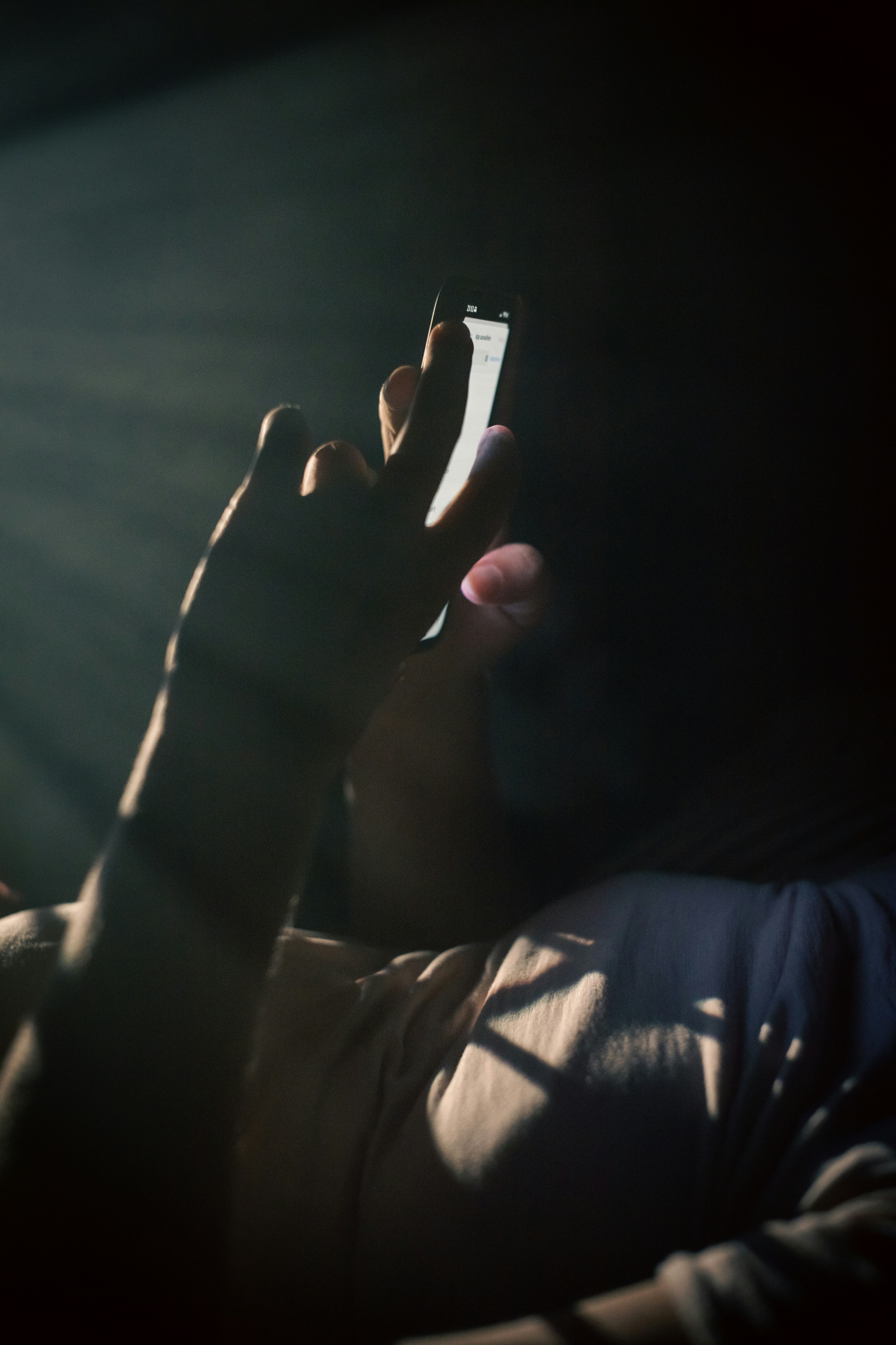 Smartphone held up by a person in a dimly lit room, dark background with soft glow