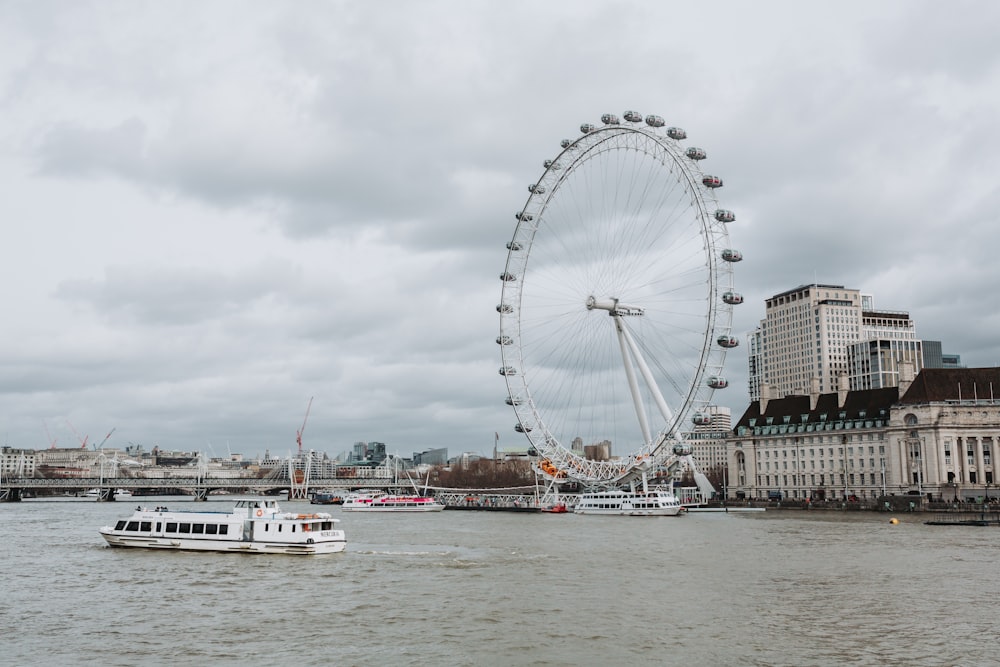 uma roda gigante ao lado de um rio com London Eye ao fundo