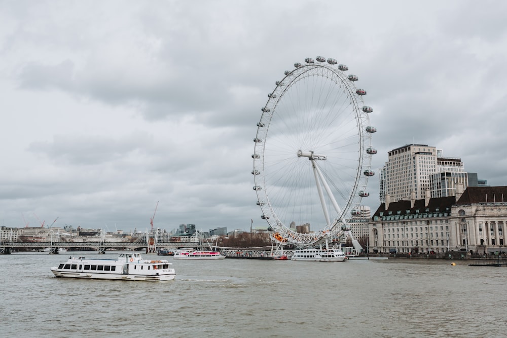 a ferris wheel next to a river with London Eye in the background