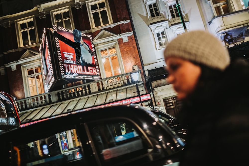 a person in a hat and coat standing in front of a building