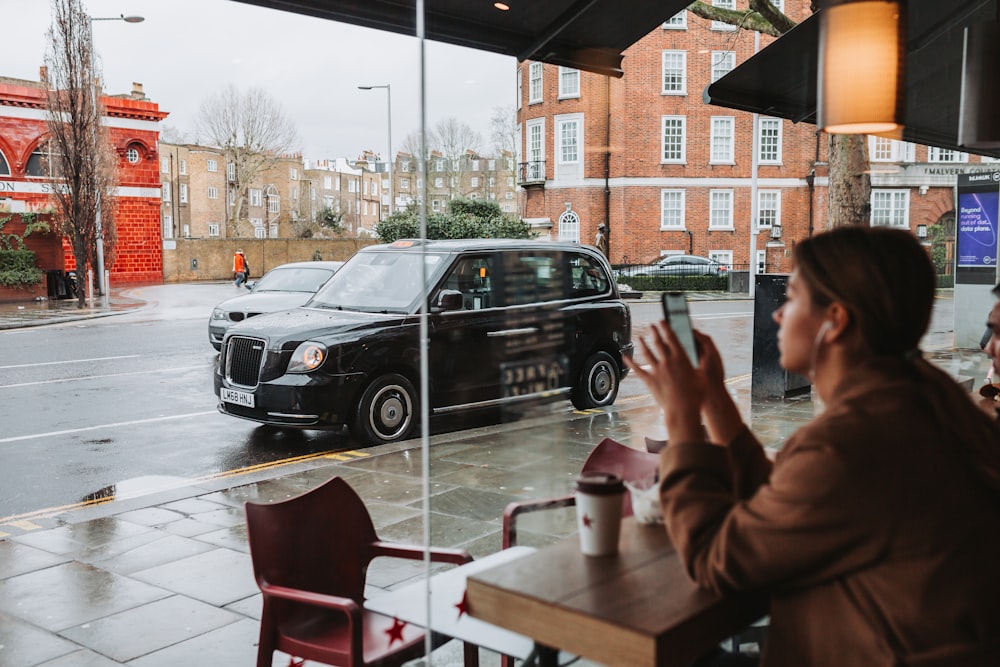 a person sitting at a table looking at a car parked on a street