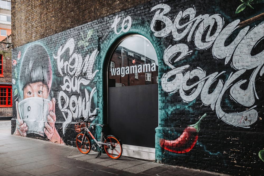 a bicycle parked next to a wall with graffiti