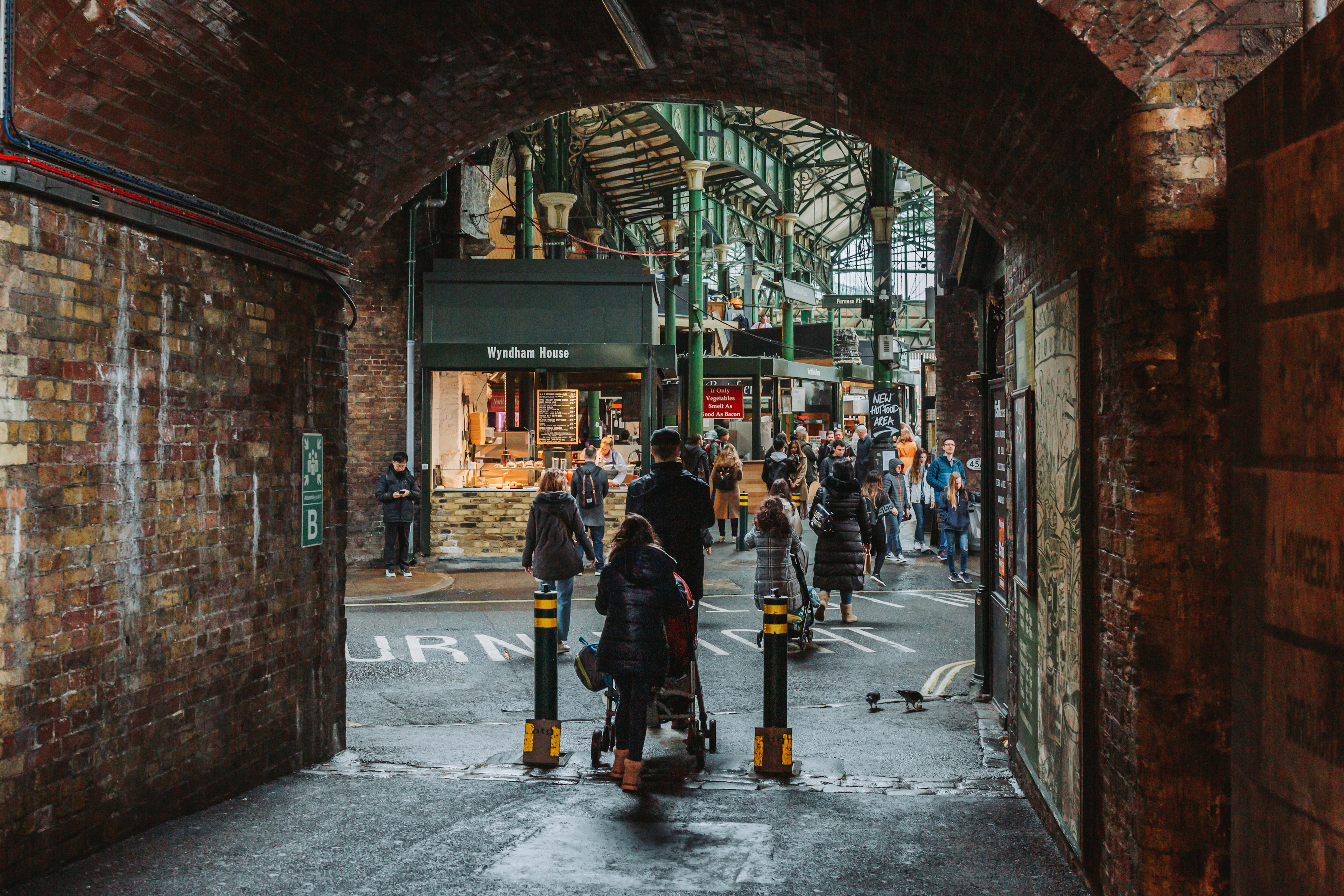 A brick archway frames a crowded lane leading into Borough Market.