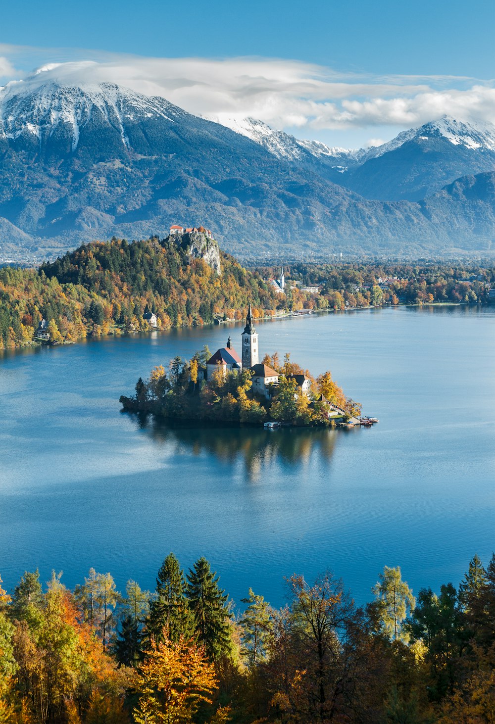 a small island with a building on it surrounded by trees and mountains