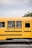 A smiling school bus driver using a smartphone while parked next to a school.