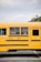 A smiling school bus driver using a smartphone while parked next to a school.