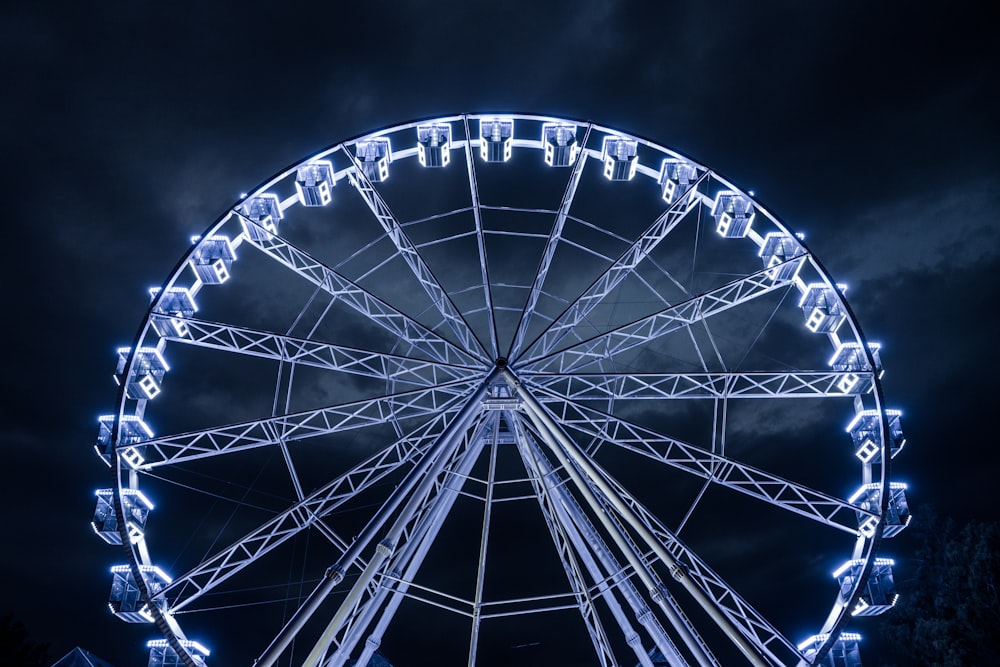 a large ferris wheel at night with Wheel of Manchester in the background