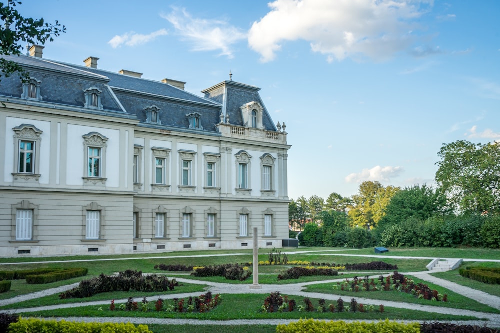 a large white building with a garden in front of it