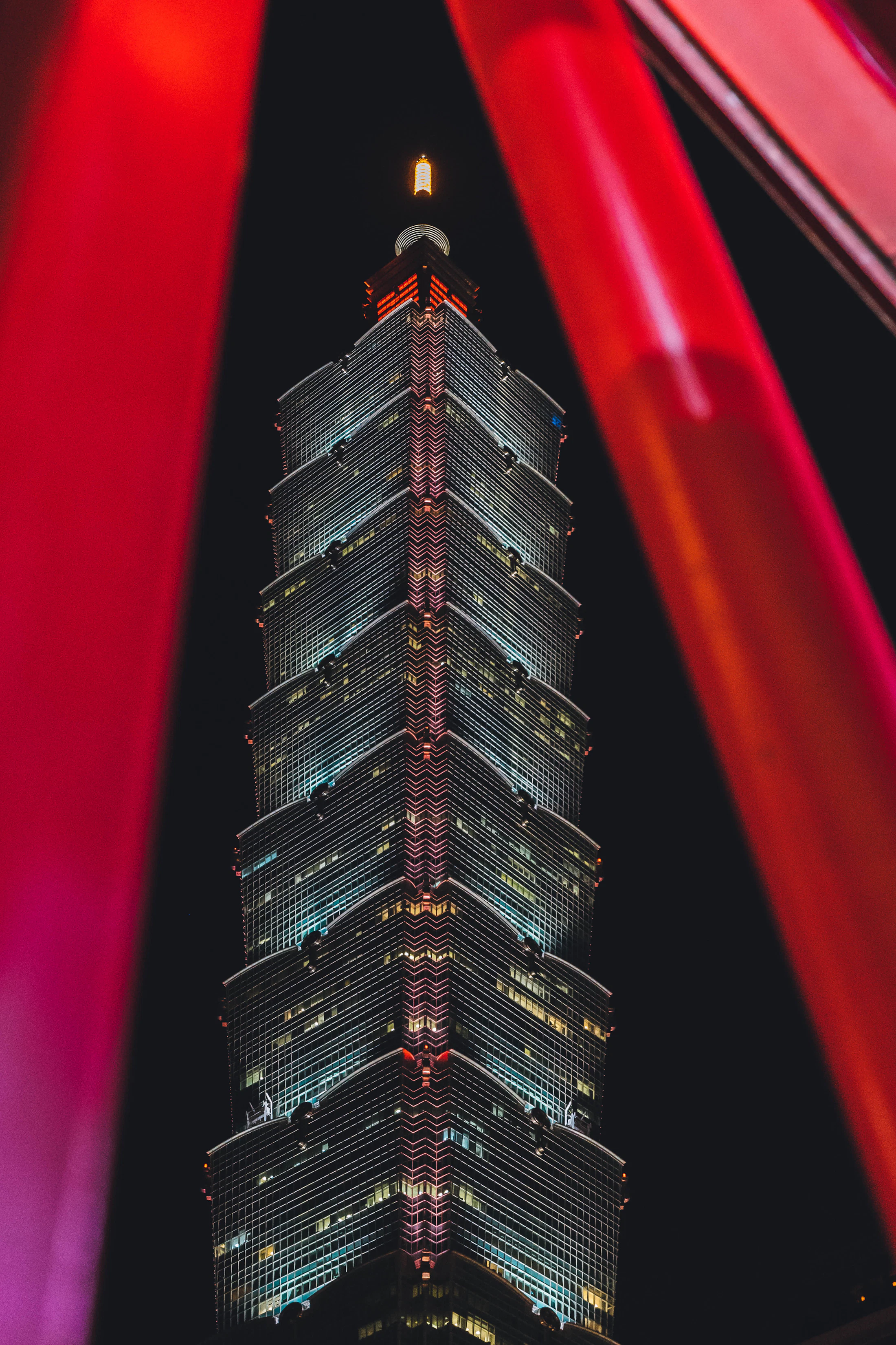 Taipei 101 above the lit city at night, cinematic skyline