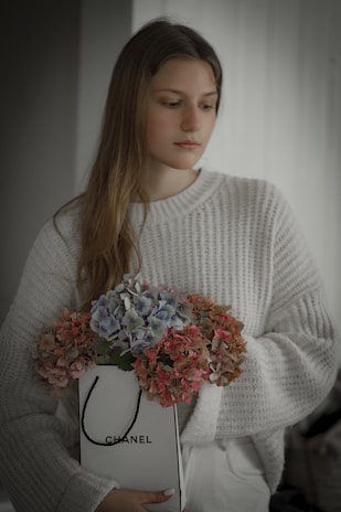 A happy customer holding a rented Chanel bag, smiling in a cozy, stylish living room.