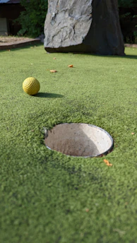 Close-up of a freshly installed backyard putting green with smooth artificial turf and golf cup.