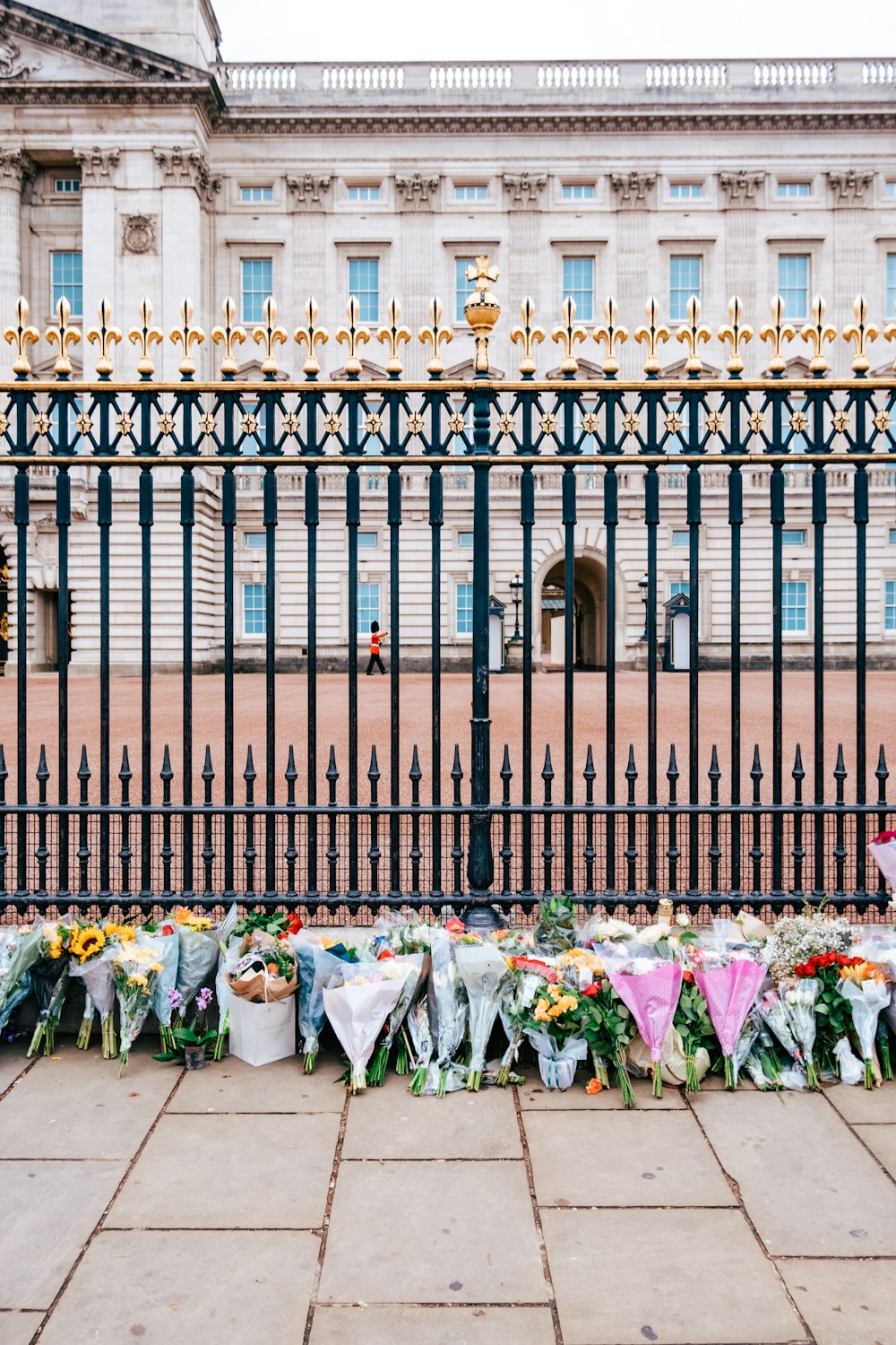 a fence with flowers and a building in the background