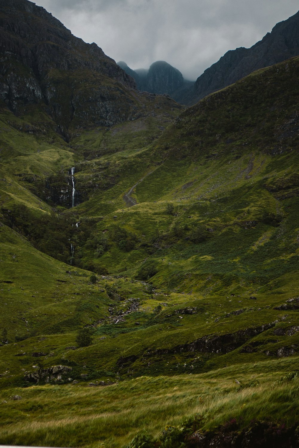 a grassy valley with a few people walking on it