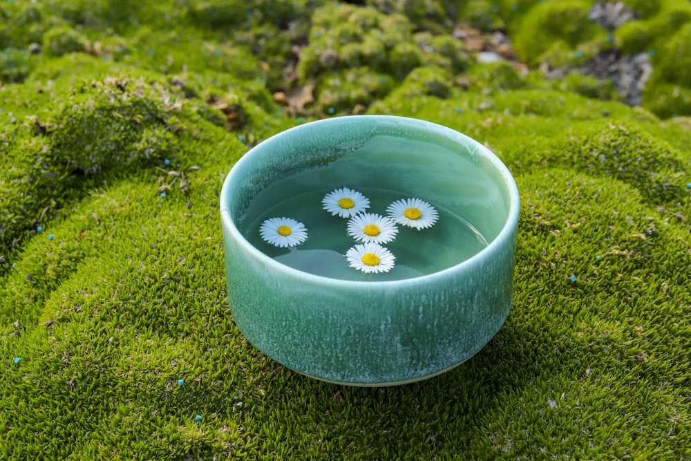 a green bowl with flowers in it