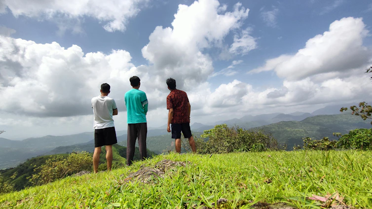 Three team members of Kaimoa Consulting standing together with the Big Island landscape in the background.